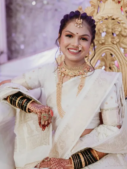 A joyful and confident bridal portrait. The bride, dressed in a stunning white saree, smiles warmly for the camera. This photo captures her personality and the happiness of the day.