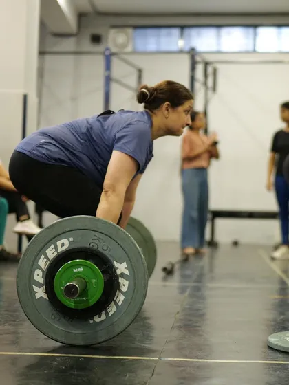 A female athlete setting up for a heavy deadlift. Strength has no gender here. We empower everyone to lift heavy, lift safely, and discover the strength they never knew they had.