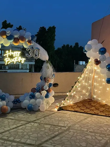 A slightly different angle of the 30th birthday terrace setup, showing the full arrangement of the balloon arch and the inviting fairy light tent.