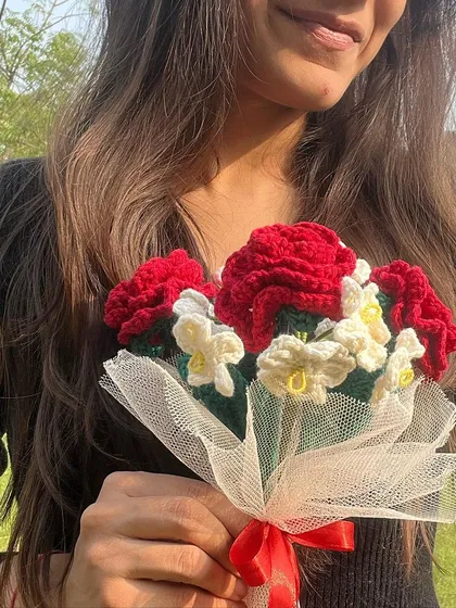 A close-up of our romantic red rose and forget-me-not bouquet, held by a model. The detail in each petal is a testament to our artisans' skill.