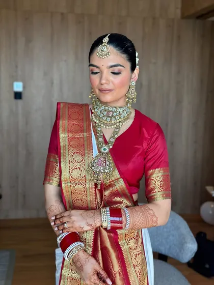 A serene portrait of the bride. The soft, neutral tones of the makeup allow the vibrant colors of her saree and jewelry to take center stage.