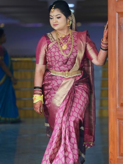 A beautiful portrait of a bride in her muhurtham attire. The rich purple silk saree is draped elegantly, and the hairstyle is a classic updo.