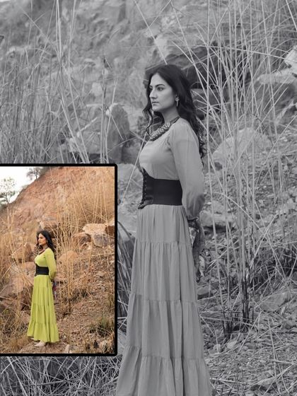A full-length shot from the 'Boho Barren' portfolio. The tiered, long flowy dress paired with a corset-style belt creates a beautiful silhouette against the natural, rustic background.