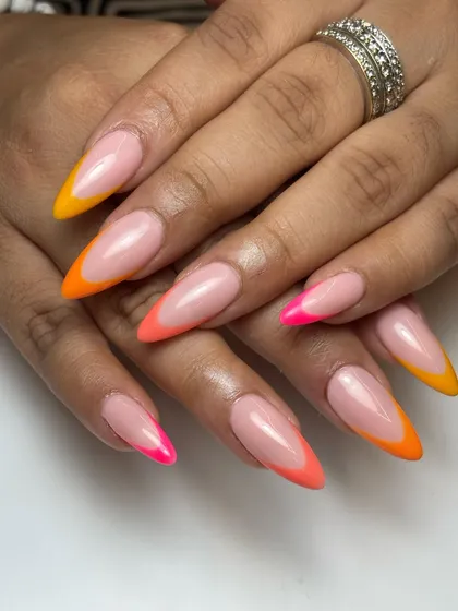 I love a modern twist on a classic. This sunkissed look features sharp, stiletto-shaped nails with a vibrant neon French tip gradient, blending from hot pink to sunny orange and yellow.