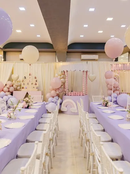 The full dining hall at the princess party, showing the long tables, floating balloons, and the grand stage in the background.