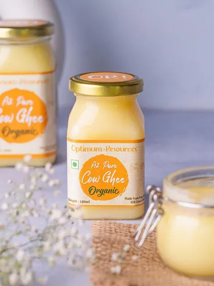 A clean and simple product shot of A2 Cow Ghee jars. The use of a burlap mat and delicate white flowers gives the product an organic and pure feel.