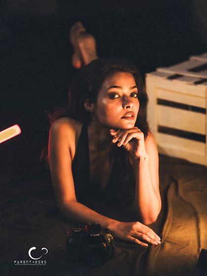 A relaxed, full-body pose that feels natural and unforced. The low lighting creates a cozy and intimate atmosphere.