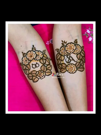 The arm design for this engagement mehendi features lovely floral wreaths with the couple's initials and interlocking rings.