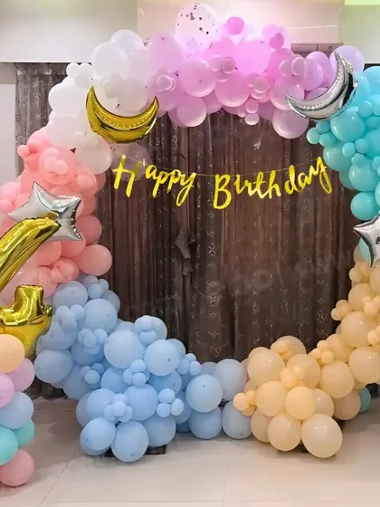 A dreamy pastel-colored birthday setup with a circular balloon arch, moon and star foil balloons, and a number '4' balloon.