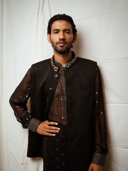 A confident, three-quarter length shot of a male model in a contemporary ethnic jacket. This pose is ideal for lookbooks, as it shows how the garment fits and can be styled.
