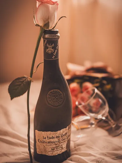 A beautifully lit shot of the vintage wine bottle on a bed, with soft, warm light creating a romantic and nostalgic mood.