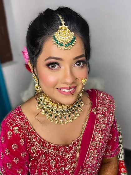 A perfect portrait of the bride, Neha. Her makeup is flawless, with a beautiful blend of colors that enhance her features and match her vibrant outfit.