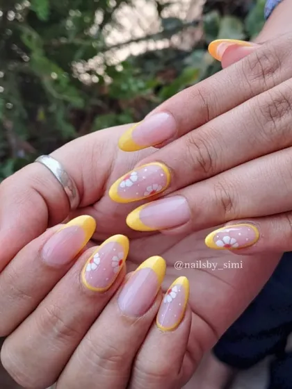 Perfect for summer! These yellow French tips are decorated with tiny, delicate floral details for a cute and fresh look.