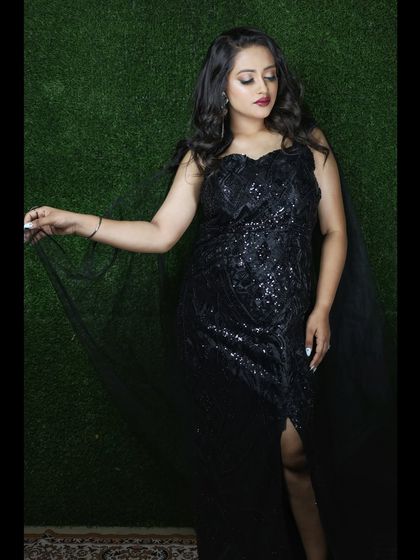 This black sequined gown is a timeless choice for any formal event. The thigh-high slit and sheer cape add a modern, glamorous touch.