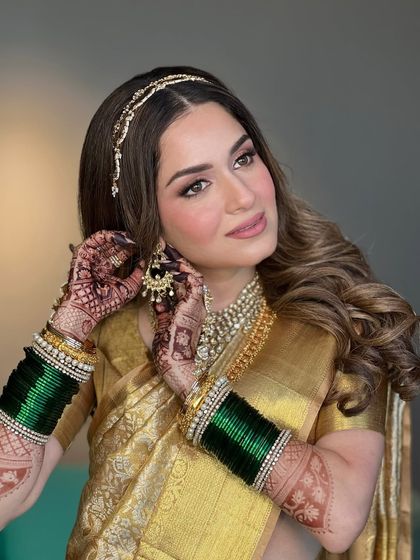 A candid moment of the bride adjusting her earring. Her glowing skin and soft smile are the highlights of this shot, showcasing a look that is both elegant and full of life.