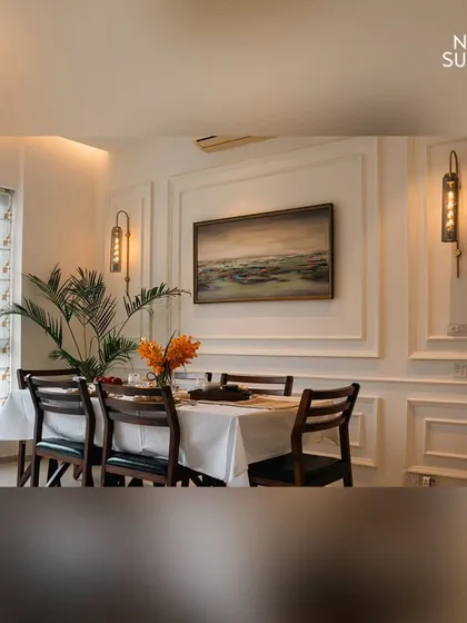This angle of the classic contemporary dining room highlights the symmetrical arrangement of the wall sconces and mouldings. This structured design approach adds a sense of formal elegance and balance to the space.