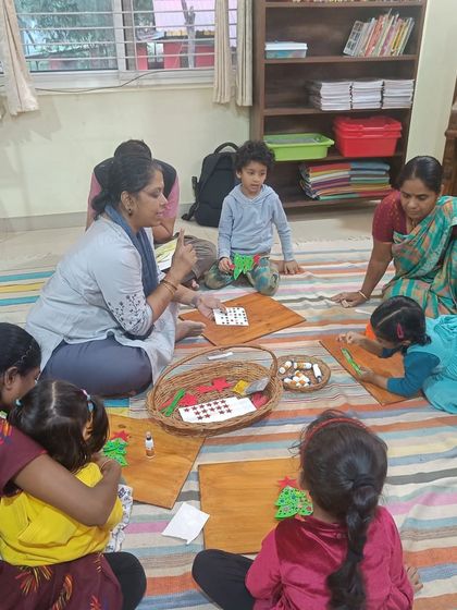 Children work on their Christmas crafts, carefully assembling their paper trees. These activities are designed to be fun and achievable for little hands.