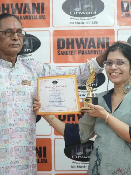 An adult student smiles proudly with her guru after receiving her art award.