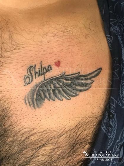 A name and wing tattoo on the chest. The name "Shilpa" is accompanied by a beautifully shaded angel wing.