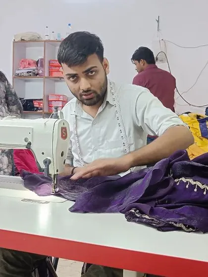 Here, one of my skilled karigars is at his sewing station, carefully stitching a deep purple fabric. His focused attention is key to creating the strong seams and clean lines that define our custom tailoring and upcycling work.