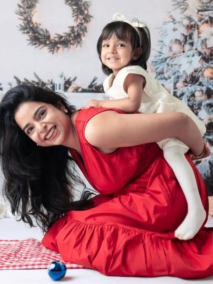 A joyful mother and daughter moment during our Christmas mini sessions. The festive backdrop and playful piggyback ride capture the holiday spirit perfectly.