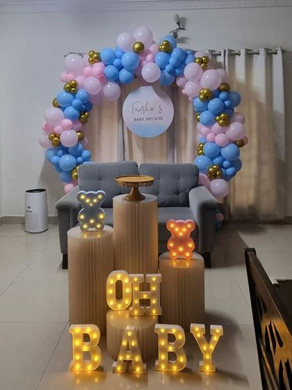 A cute 'Oh Baby' teddy bear themed baby shower setup with a pink and blue balloon ring and marquee letters.