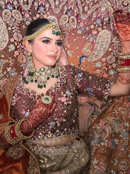 A close-up of the peacock lehenga, showing the detailed embroidery and the bride's pose.