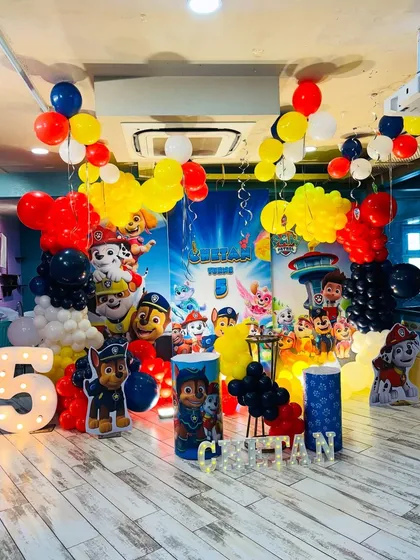 A full-room Paw Patrol birthday decoration. This setup includes a large character backdrop, multiple character cutouts, a light-up number '5', and balloon arrangements filling the space with color and excitement.