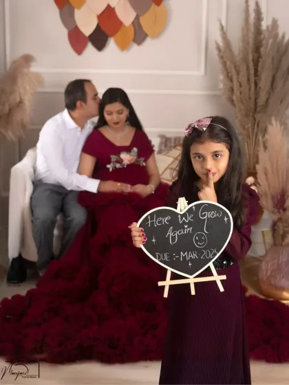 "Here we grow again!" This shot beautifully includes the older sister, who holds a sign and shares a secret with the camera. A perfect family portrait.