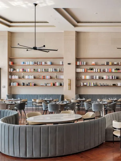 The repetition of form and the careful arrangement of furniture create a sense of rhythm and order in this large dining space. The curved banquettes soften the geometry of the room, making the expansive area feel more approachable and comfortable.