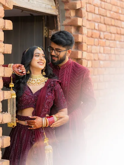 A sweet, romantic moment between a bride and groom. The way he looks at her and her joyful smile says everything. The rustic brick wall adds a warm, charming texture.