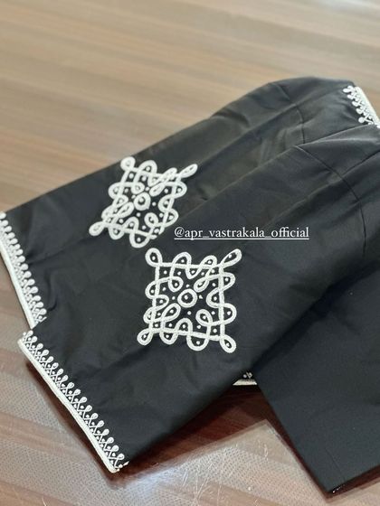 A black blouse with white threadwork in a traditional kolam pattern.