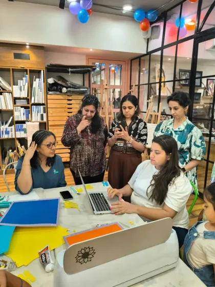 Participants in a Cricut workshop watch intently as a design is being cut, learning how to use modern crafting tools to create custom items.