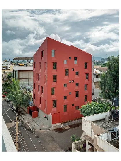 The building's form is a direct result of its innovative sectional design, which stacks living spaces efficiently. This aerial shot shows its relationship to the surrounding low-rise buildings.