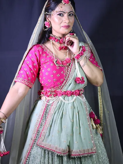 A portrait of the client in her mint green and pink lehenga, showcasing her floral jewellery and beautiful makeup.