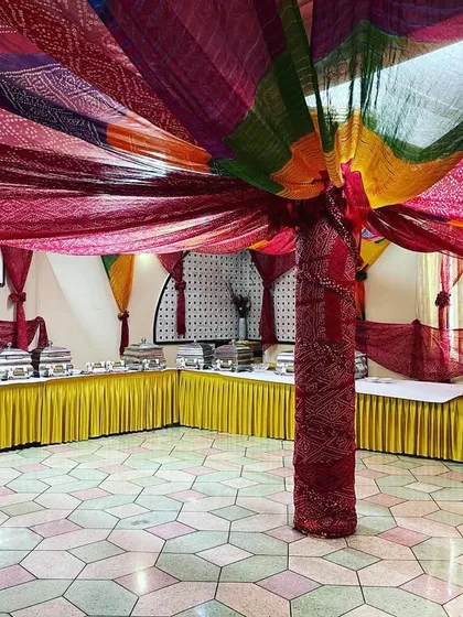 A vibrant, Rajasthani-themed buffet setup for a sangeet ceremony. The colourful bandhani drapes and traditional decor create a festive atmosphere for guests.