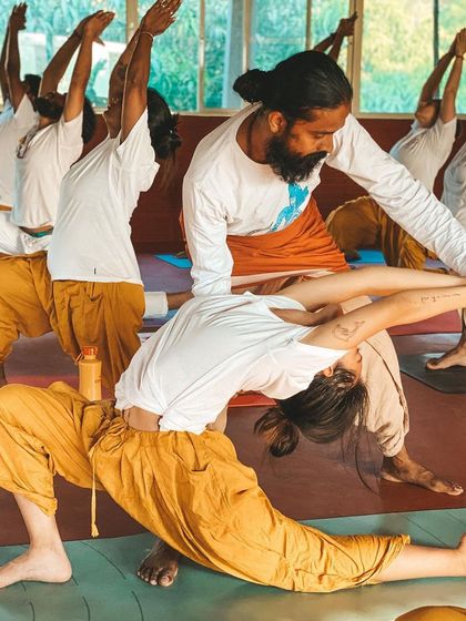 I guide a student through a reverse prayer lunge, a posture that opens the shoulders and hips simultaneously. My adjustments help refine the pose, allowing for a deeper and more beneficial stretch.