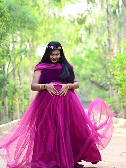 A beautiful outdoor shot in a flowing magenta maternity gown. The sheer fabric and floral crown create a soft, bohemian vibe perfect for a nature-themed pregnancy shoot.