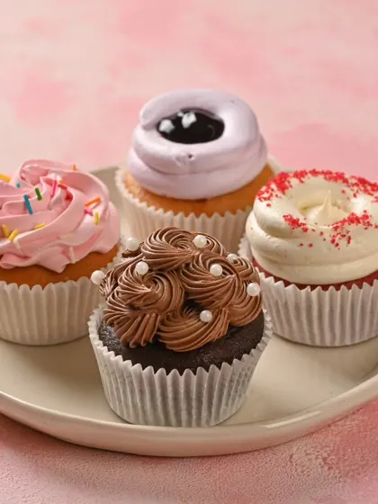 A simple plate of our assorted eggless cupcakes. We offer a variety of flavors like classic chocolate, strawberry sprinkle, red velvet, and blueberry, perfect for any craving or celebration.