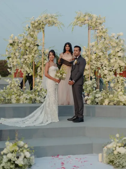 A pristine and elegant Christian wedding ceremony, with the couple standing before a beautiful floral arch of white hydrangeas and roses. I specialize in creating sophisticated and modern wedding aesthetics.