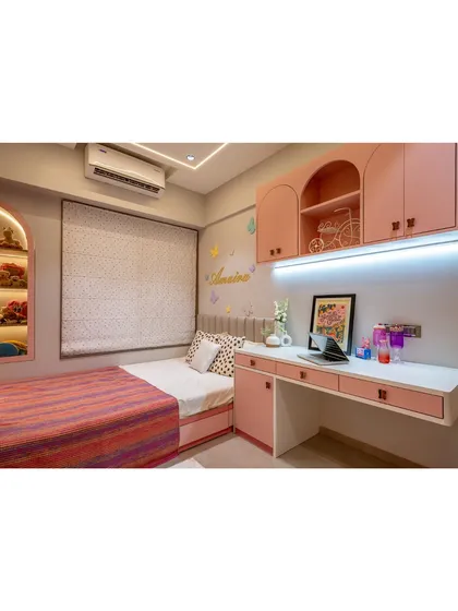A wider view of the pastel pink bedroom, showing the bed, study desk, and wardrobe. The cohesive color scheme and arched motifs create a dreamy and harmonious space.