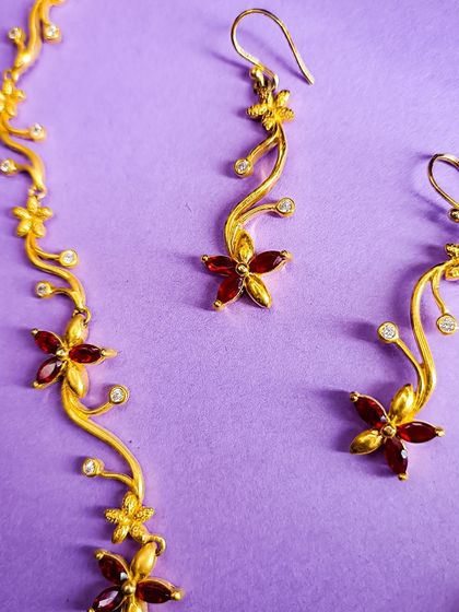 A close-up of the matching earrings for the gold-plated floral necklace set. The design mirrors the necklace's delicate vine motif.