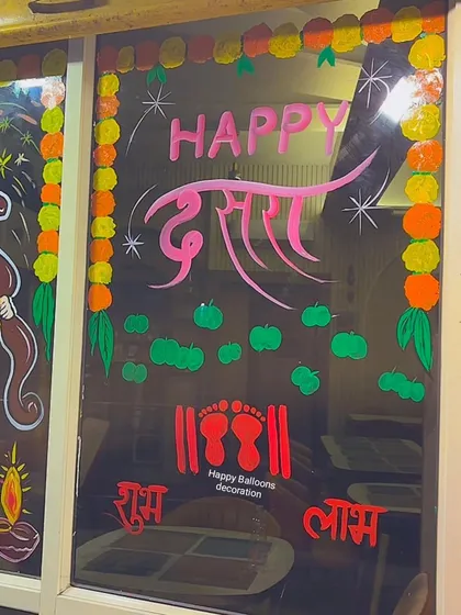 A 'Happy Dussehra' message painted on a glass door, featuring auspicious footprints and 'Shubh Labh' text to welcome prosperity.
