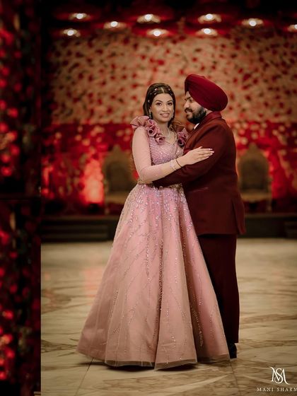A full-length portrait showcasing the couple's elegant engagement attire against a rich red floral backdrop.