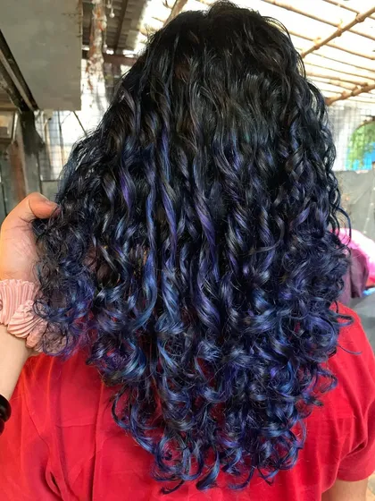 Rocking this blue and purple hair like a boss. This magical transformation on curly hair was done using bleach to achieve those vivid jewel tones.