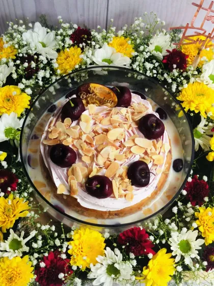 An overhead shot of the Cherry Almond Tres Leches hamper, highlighting the beautiful circular arrangement of the flowers around the cake.