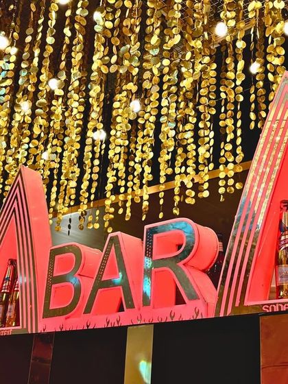 A bold and modern bar sign, lit in red, making it a clear and stylish focal point for the beverage station at a sangeet or cocktail event.