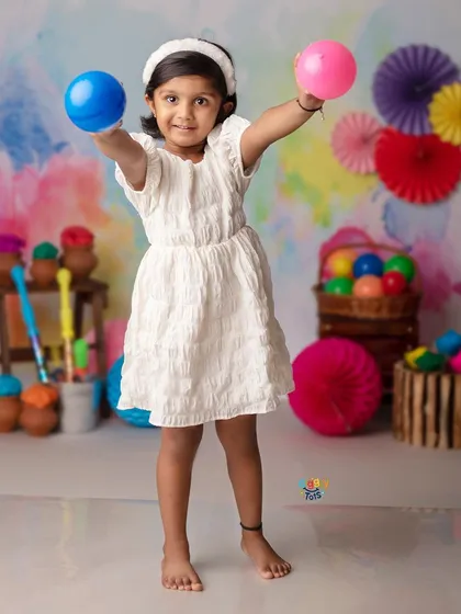 Another angle of our colorful Holi setup, with a happy girl ready to play with water balloons.