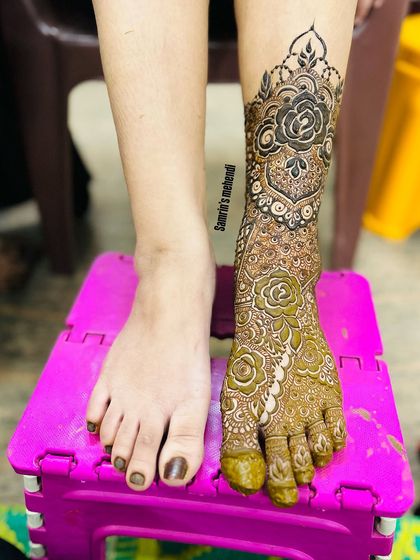 A before-and-after style shot, showing one leg bare and the other beautifully adorned with henna.