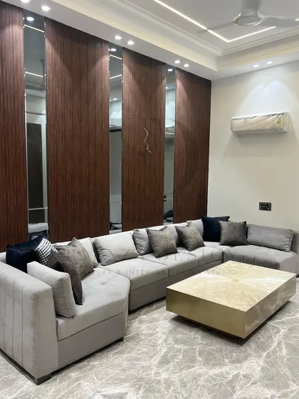 This large, grey L-shaped sectional provides ample seating for a family room. It is paired with a striking center table made of selenite with a brass base, blending comfort with high-end materials.